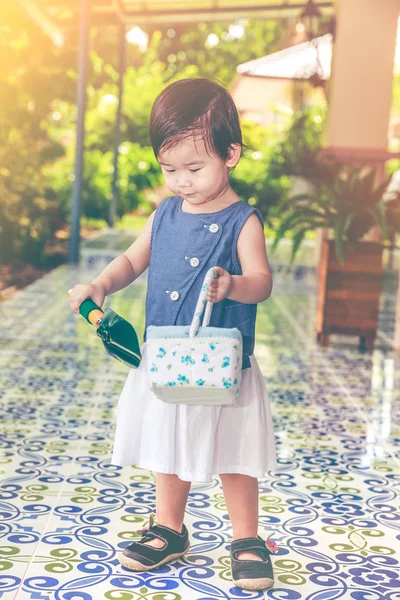 Ein asiatisches Kind hält Schaufel und Korb bereit für die Gartenarbeit. Vintage-Ton. — Stockfoto