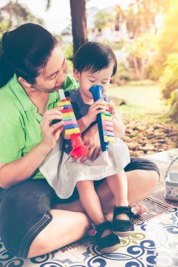 Plastik boru boru ile kızının oynarken Asya anne. Vintage sesi.