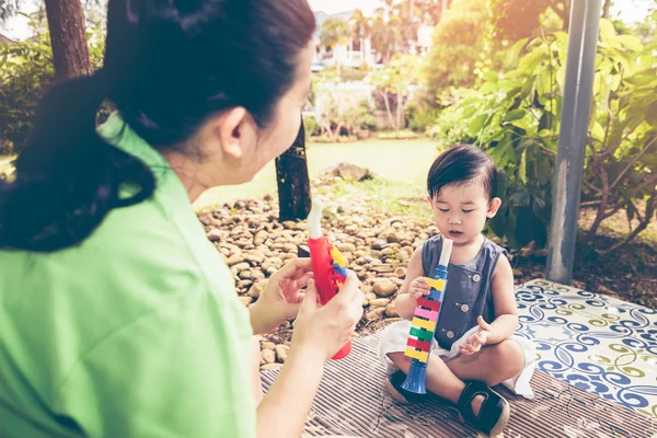Asian mother playing plastic trumpet pipe with her daughter. Vintage tone. — Stock Photo, Image