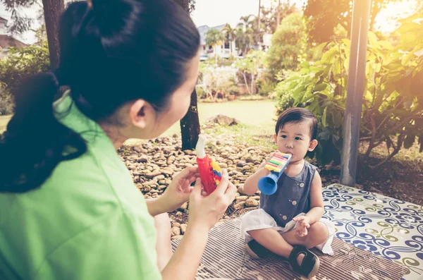 Plastik boru boru ile kızının oynarken Asya anne. Vin — Stok fotoğraf