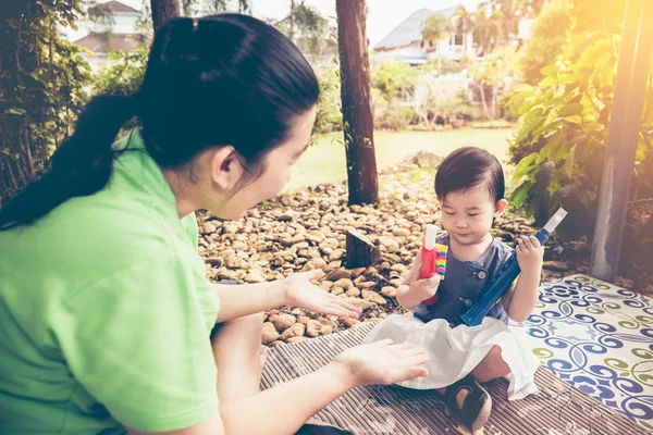 Mère asiatique jouant de la trompette en plastique avec sa fille. Ton vintage . — Photo