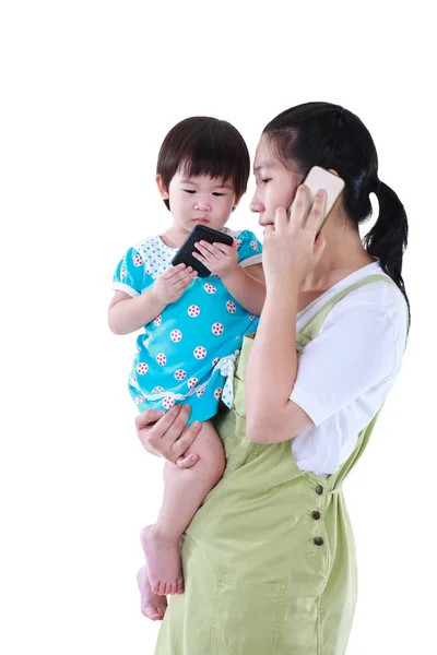 Busy asian mother using smartphone and carrying her daughter. Isolated on white background. — Stock Photo, Image