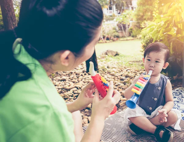 亚洲妈妈打塑料喇叭管与她的女儿。Vin — 图库照片