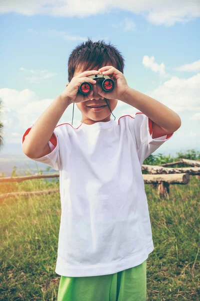 Aziatische jongen kijken door een telescoop. Kind ontspannen vakantie. Vintage Toon. — Stockfoto