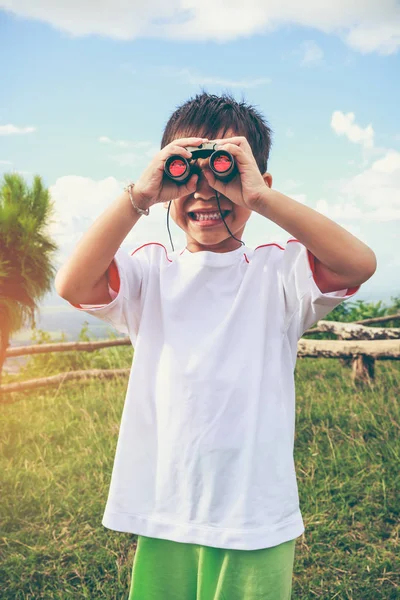 アジアの少年は望遠鏡を通して見る。子供リラックスした休日. — ストック写真