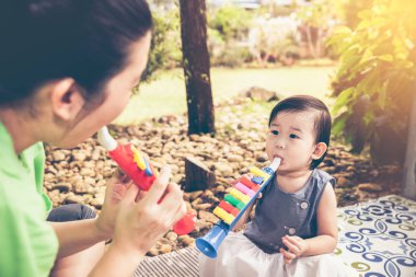 Plastik boru boru ile kızının oynarken Asya anne. Vintage etkisi sesi.