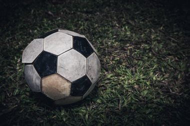 Eski futbol topu veya futbol tekme için yeşil çimenlerin üzerinde yatıyordu. Düşük anahtar resim stili.