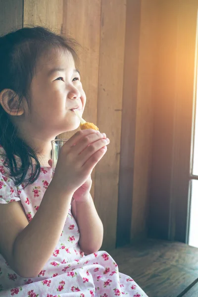 Asijské dítě s úsměvem a chutnají, obalované sýr mozzarella hole v restauraci v její oběd. — Stock fotografie