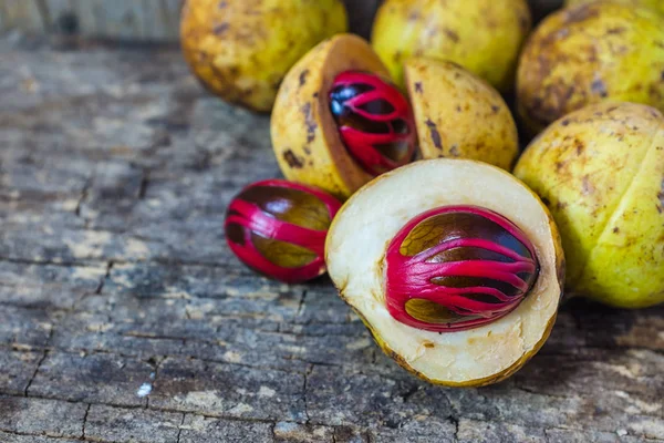 Küçük Hindistan cevizi myristica ahşap arka plan üzerinde kokulu tohum plasenta gibi kapaklı.