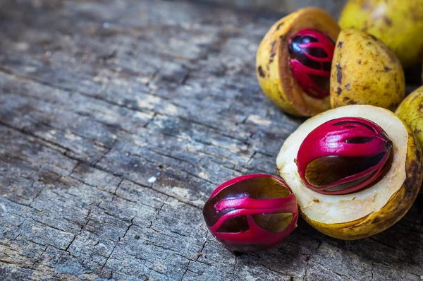 Küçük Hindistan cevizi myristica ahşap arka plan üzerinde kokulu tohum plasenta gibi kapaklı.