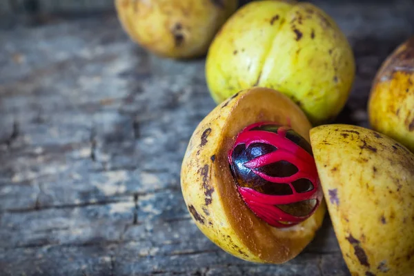 Küçük Hindistan cevizi myristica ahşap arka plan üzerinde kokulu tohum plasenta gibi kapaklı.