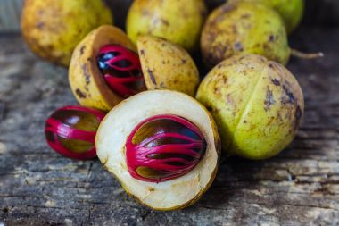Küçük Hindistan cevizi myristica ahşap arka plan üzerinde kokulu tohum plasenta gibi kapaklı.