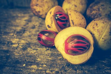 Küçük Hindistan cevizi myristica ahşap arka plan üzerinde kokulu tohum plasenta gibi kapaklı.