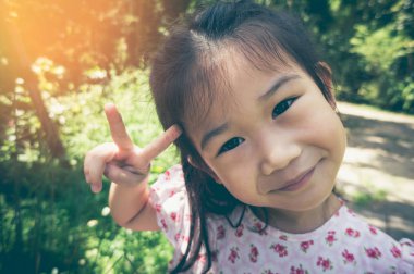 Çok güzel Asyalı çocuk gülümseyen ve güneş ışığı ile Park'ta rahatlatıcı seyahat etmek tatil.