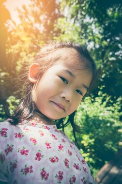 Çok güzel Asyalı çocuk gülümseyen ve güneş ışığı ile Park'ta rahatlatıcı seyahat etmek tatil.