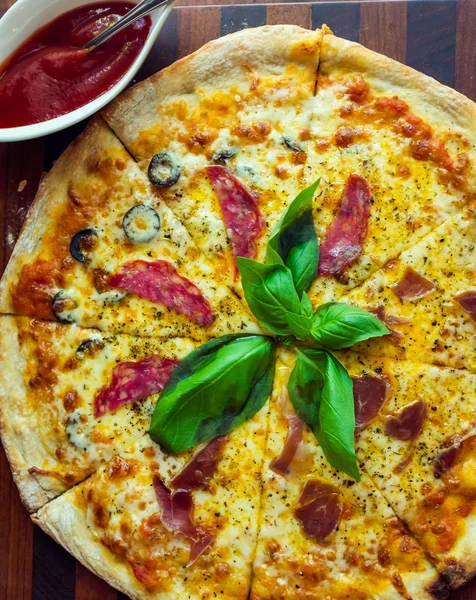 Vista superior de PIZZA con jamón, champiñones, albahaca, queso y tomate o salsa se coloca cerca . — Foto de Stock