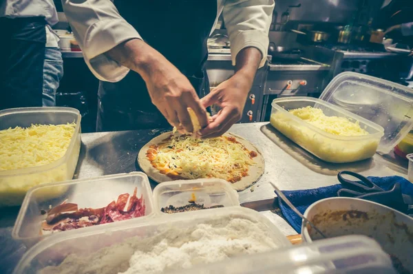 Şef mutfak at lezzetli pizza hazırlama beyaz üniformalı.