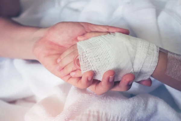 Zbliżenie dłoni rodzica, trzymając rękę dziecka w szpitalu. Vintage efekt ton. — Zdjęcie stockowe