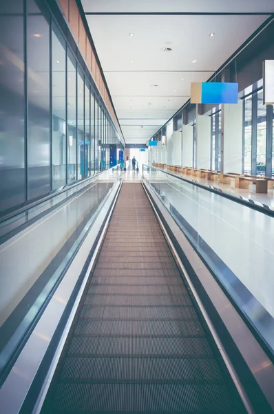 Modern long walkway of escalator moving forward at airport terminal.