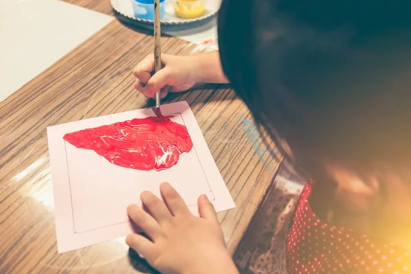 Feliz chica asiática pintando color rojo en obras de arte con pincel . — Foto de Stock