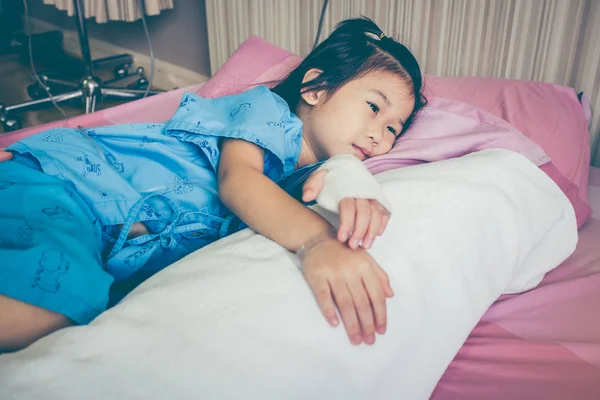 Illness asian child admitted in hospital with saline intravenous (IV) drip on hand. — Stock Photo, Image