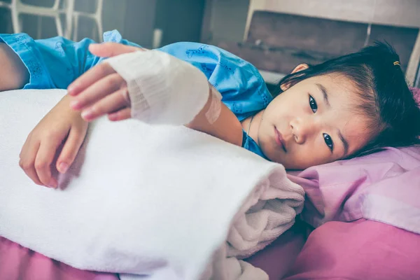 Illness asian child admitted in hospital with saline intravenous (IV) drip on hand. — Stock Photo, Image