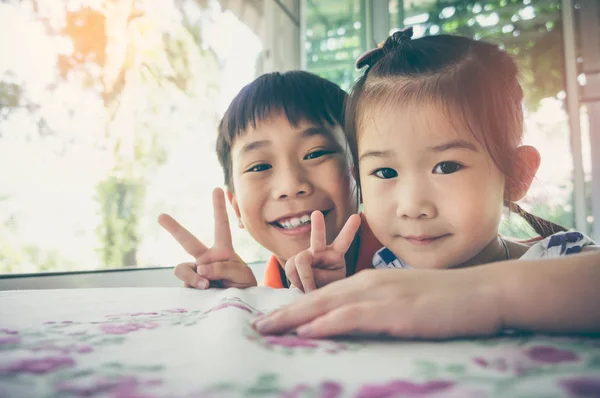 Hermano y hermana sonriendo y mostrando signo v. Tono vintage . —  Fotos de Stock