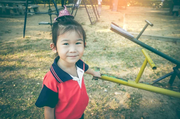 Ein asiatisches Kind steht neben einer Wippe auf einem Kinderspielplatz. Vintage-Ton. — Stockfoto