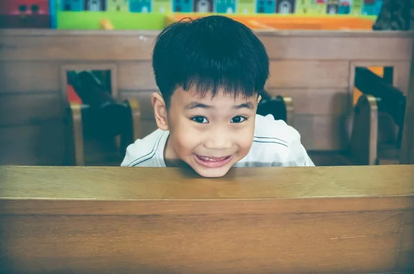 Szczęśliwe dziecko azjatyckiej uśmiechający się i głowę pojawiające się nad drewnianym stołem. — Zdjęcie stockowe