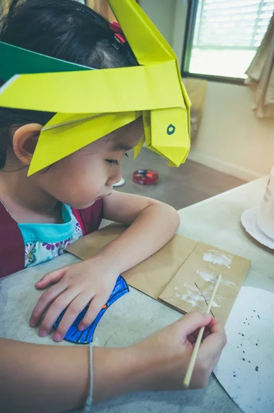 Симпатичная азиатская девушка делает ручную работу из бумаги и клея. Винтажный тон . — стоковое фото