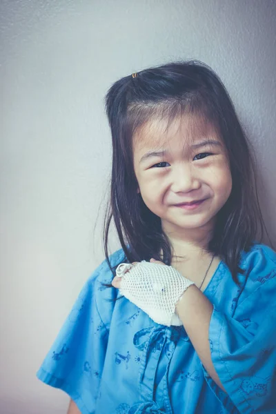 Illness asian child smiling and showing saline iv drip on her hand. Vintage tone. — Stock Photo, Image