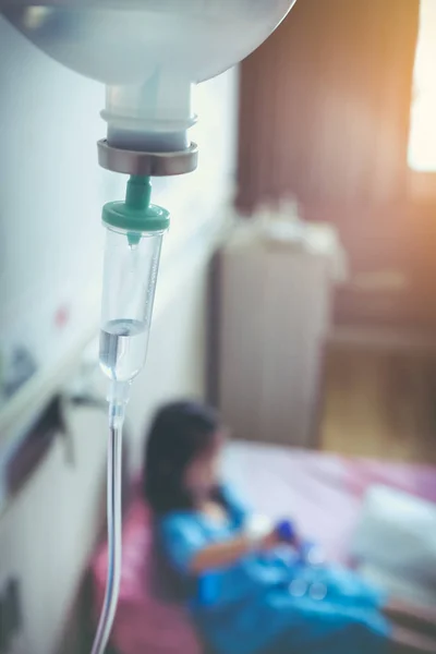 フォーカスの点滴 (Iv) と病院の病床に座っている病気アジア女の子. — ストック写真