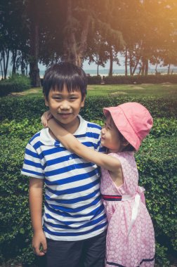 Güzel Asyalı kız onu koymak vardır kol kardeşinin omuzun çevresine. Vintage etkisi sesi.