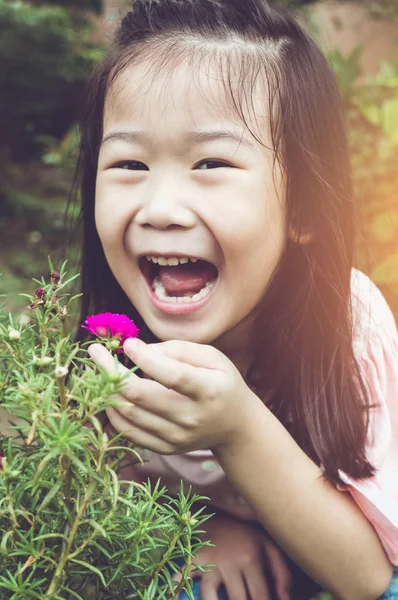 Asian child admiring for pink flowers and nature around at backyard. — Stock Photo, Image