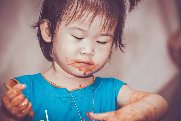 汚れた顔で食べる子。自分で行う概念。ビンテージ トーン. — ストック写真