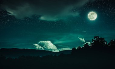 Emeral gece gökyüzünde birçok yıldız ve bulutlu silhouette dağ ve ağaçlar yukarıda manzara. Güzel parlak dolunay karanlık sesi sakin doğa üzerinde. Kendi fotoğraf makinesi ile çekilen ay.