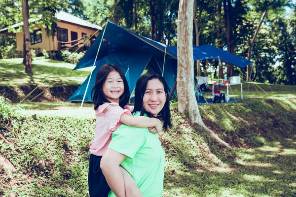 Cute asian daughter on a piggy back ride with her mother in the national park. — Stock Photo, Image