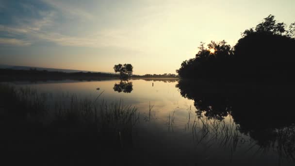 Vue tranquille sur le lac au lever du soleil. Brouillard au-dessus de l'eau le matin. Se sent frais et rafraîchissant. La lumière passe des ténèbres à la lumière .