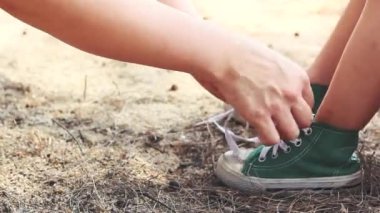 Kibar anne kızının ayakkabı bağcıklarını bağlamasına yardım ediyor. Yeşil spor ayakkabı giyen bir çocuk. Çocuklarla mutlu bir ailede bakım ve iyi ilişkiler kavramı. Yaz günü dışarıda.. 