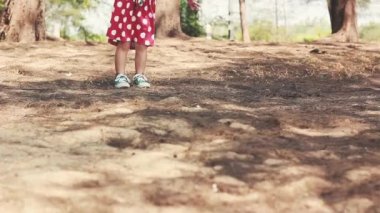 Kırmızı elbiseli ve yeşil spor ayakkabılı çocuk. Yaklaş, çocuk ayakları park yolunda yürüyor ve koşuyor. Yaz günü dışarıda.. 