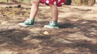 Kırmızı elbiseli ve yeşil spor ayakkabılı çocuk. Yaklaşın, çocuk ayakları park yoluna doğru yürüyor. Yaz günü dışarıda.. 