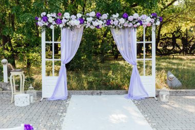 Ziyaret töreninde düğün dekoru, menekşe çiçekli beyaz bir düğün kemeri.