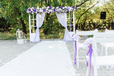 Ziyaret töreninde düğün dekoru, menekşe çiçekli beyaz bir düğün kemeri.