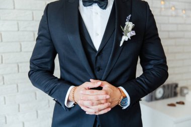 Siyah takım elbiseli damat, beyaz gömlekli bir smokin ve düğmeli bir delik.