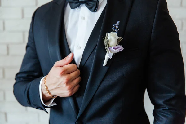 the groom in a black wedding suit, a tuxedo in a white shirt and a buttonhole