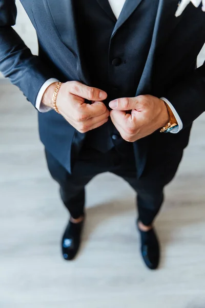 the groom in a black wedding suit, a tuxedo in a white shirt and a buttonhole