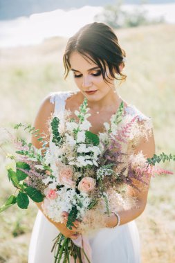 Şatafatlı beyaz gelinlikli gelin gün batımında doğada