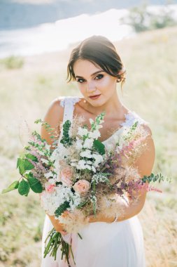 Şatafatlı beyaz gelinlikli gelin gün batımında doğada