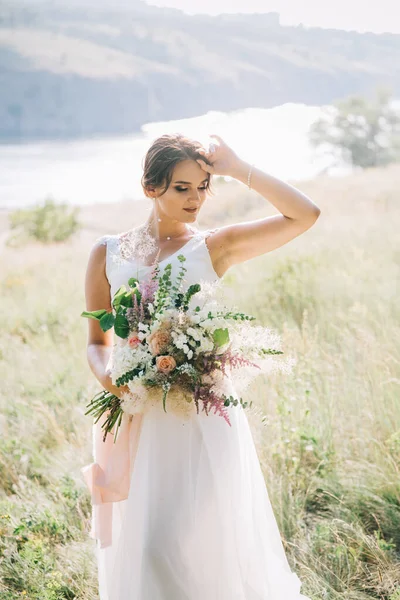 Şatafatlı beyaz gelinlikli gelin gün batımında doğada