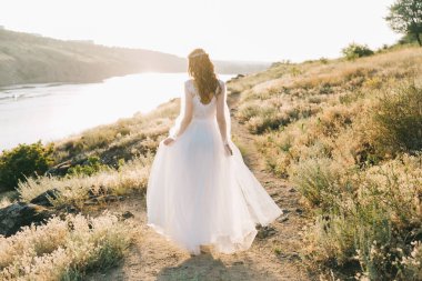 Şatafatlı beyaz gelinlikli gelin gün batımında doğada